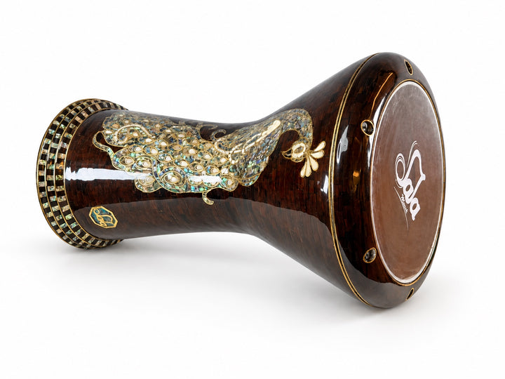 Sala Amber Peacock Sombaty darbuka på siden, som viser det Sala-merkede trommeskinnet og et blekt påfuglmotiv på en mørk ravbrun mosaikkbakgrunn.